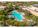 Aerial view of a community pool area featuring a cross-shaped pool, lounge chairs, and cabanas amidst mature landscaping at 7710 E Gainey Ranch E Rd # 115, Scottsdale, AZ 85258