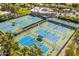 Aerial view of blue tennis courts surrounded by green space and community buildings and lush landscaping in a sunny setting at 7710 E Gainey Ranch E Rd # 115, Scottsdale, AZ 85258