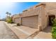 Exterior view of tan townhomes, featuring two-car garages, sidewalks, and desert landscaping at 8540 N Central Ave # 6, Phoenix, AZ 85020