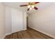 This bedroom features a ceiling fan, wood flooring, baseboards, and a large closet with white doors at 11829 W Rosewood Dr, El Mirage, AZ 85335