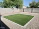Private backyard showcasing desert landscaping and a synthetic grass patch with block wall fencing at 1187 E Cowboy Cove Trl, San Tan Valley, AZ 85143