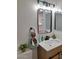 A modern bathroom with wooden vanity, quartz countertop, black hardware and decorative mirror at 1187 E Cowboy Cove Trl, San Tan Valley, AZ 85143
