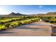 Aerial view showcasing the land for sale in blue, complemented by a picturesque golf course and mountain views at 30660 N 120Th Ln, Peoria, AZ 85383