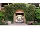 Lush courtyard entrance with arched wooden doorway covered in greenery and featuring manicured landscaping at 30660 N 120Th Ln, Peoria, AZ 85383