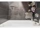 Modern shower with dark gray tiling, a white tub, and convenient shelving for toiletries at 7756 N 19Th Ln, Phoenix, AZ 85021