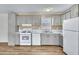 This kitchen includes white appliances, light gray cabinets, marble countertops, and vinyl floors at 320 E Mckellips Rd # 186, Mesa, AZ 85201