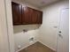 Practical laundry area with upper cabinets, tile flooring, and essential hookups at 12041 W Carlota Ln, Sun City, AZ 85373