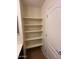 White shelving unit with multiple shelves for storage, adjacent to a closed white door at 12041 W Carlota Ln, Sun City, AZ 85373