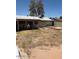 The backyard with a covered patio area extending from the home with scattered vegetation at 18415 N 33Rd Ave, Phoenix, AZ 85053
