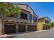 Three-story condo exterior with multiple garages, beige stucco, and flowering tree in the foreground at 2725 E Mine Creek Rd # 1149, Phoenix, AZ 85024