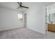 Unfurnished bedroom features neutral carpet, ceiling fan, natural light, and an ensuite bathroom at 2732 N 217Th Ave, Buckeye, AZ 85396