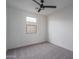 A modern bedroom with neutral gray carpet, a window for natural light, and a ceiling fan at 2732 N 217Th Ave, Buckeye, AZ 85396