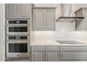 Gourmet kitchen with stainless steel appliances, double ovens, sleek cabinetry, and a modern range hood at 578 E Las Puertas Ln, Queen Creek, AZ 85140