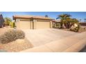 Two-car garage with tan colored doors and long driveway at 17156 W Lachlan Ct, Surprise, AZ 85387