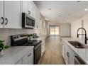 Open concept kitchen flows into the living room, featuring white cabinets, stainless steel appliances, and ample natural light at 18450 E Camila Dr, Gold Canyon, AZ 85118