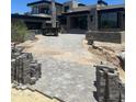 View of a stone paved driveway leading up to a modern house, surrounded by construction and desert landscaping at 37445 N 104Th Pl, Scottsdale, AZ 85262