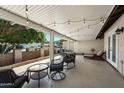 Relaxing covered patio with string lights, multiple seating arrangements, and a view of the front yard at 1296 Leisure World --, Mesa, AZ 85206