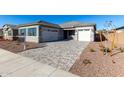 New construction home with a two-car garage and a brick paved driveway at 16412 W Avenida Del Sol --, Surprise, AZ 85387