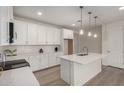 Modern white kitchen featuring an island with a sink, pendant lights, and white subway tile backsplash at 18812 E Elizar Dr, Gold Canyon, AZ 85118