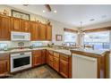 Well-lit kitchen featuring wood cabinets, granite countertops, and white appliances at 18315 W Santa Alberta Ln, Goodyear, AZ 85338