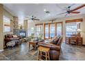 Cozy living room with leather furniture, ceiling fans, and a stone fireplace at 18315 W Santa Alberta Ln, Goodyear, AZ 85338