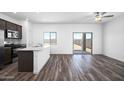Open-concept living space featuring wood-look flooring, modern ceiling fan, and sliding glass doors to the backyard at 24636 W St Catherine Ave, Buckeye, AZ 85326