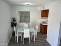 Bright dining area features a glass table, white chairs, modern art, and wood-look floors at 4032 W Reade Ave, Phoenix, AZ 85019