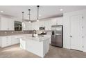 Modern kitchen with white cabinets, island, and stainless steel appliances at 40503 W Wade Dr, Maricopa, AZ 85138