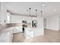 Modern kitchen with white cabinets, island, and stainless steel appliances at 40503 W Wade Dr, Maricopa, AZ 85138