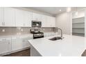 Modern kitchen featuring white cabinets, quartz countertops, and stainless steel appliances at 19645 W Cartwright Ave, Buckeye, AZ 85396