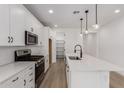 Modern kitchen with white cabinets, stainless steel appliances, an island, and stylish pendant lighting at 40075 W Elm Dr, Maricopa, AZ 85138