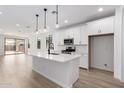 Bright open floorplan with a modern kitchen featuring an island, stainless appliances, and white cabinets at 40075 W Elm Dr, Maricopa, AZ 85138