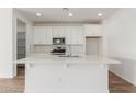 Modern kitchen with white cabinets, quartz countertops, and stainless steel appliances at 40115 W Elm Dr, Maricopa, AZ 85138