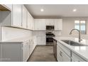 Modern kitchen featuring white cabinets, quartz countertops, and stainless steel appliances at 21641 N Daniel Dr, Maricopa, AZ 85138