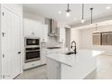 Modern kitchen features white cabinets, stainless steel appliances, an island with sink, and tile backsplash at 20262 W Hollyhock St, Buckeye, AZ 85396