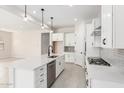 Open kitchen featuring white cabinets, stainless steel dishwasher, gas cooktop, island sink, and pendant lights at 20262 W Hollyhock St, Buckeye, AZ 85396