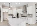 Modern kitchen with white cabinets, island sink, stainless steel appliances, and stylish pendant lighting at 20262 W Hollyhock St, Buckeye, AZ 85396