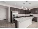 Modern kitchen with island, stainless steel appliances, and dark cabinets at 40519 W Wade Dr, Maricopa, AZ 85138