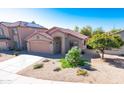 Attractive single-story home featuring a desert landscape, two-car garage, and a red tile roof under a bright blue sky at 10649 W Monte Vista Rd, Avondale, AZ 85392