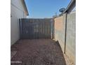 View of the enclosed gravel side yard, surrounded by a cinder block and wood fence for privacy at 3222 W Wagoner Rd, Phoenix, AZ 85053