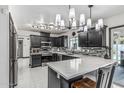Modern kitchen featuring dark cabinets, stainless steel appliances, island with marble countertop and backsplash detail at 4020 W Anderson Dr, Glendale, AZ 85308