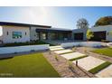 A modern home with lush turf landscaping and a walkway to the stone-clad front entry at 12232 N 65Th Pl, Scottsdale, AZ 85254