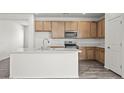 Bright kitchen featuring an island with a sink, stainless steel appliances, and wooden cabinets at 5729 S 243Rd Dr, Buckeye, AZ 85326