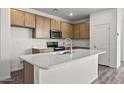 Modern kitchen featuring an island with seating, stainless steel appliances, and wooden cabinets at 5729 S 243Rd Dr, Buckeye, AZ 85326