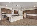 Spacious kitchen featuring an island with white countertop, wood cabinets, and stainless steel appliances at 19679 E Estrella Rd, Queen Creek, AZ 85142
