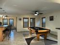 Spacious game room features a pool table, stylish ceiling fan, and bright natural light at 45737 W Ranch Rd, Maricopa, AZ 85139