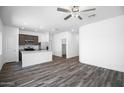 Open-concept living area featuring wood-look flooring and a ceiling fan, open to modern kitchen at 24594 W St Catherine Ave, Buckeye, AZ 85326