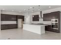 Spacious kitchen featuring dark wood cabinets, a white quartz island and stainless steel appliances at 19539 E Estrella Rd, Queen Creek, AZ 85142