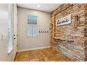 Inviting entryway with a stone feature wall, wood shelf, and tile flooring at 7351 W Palo Brea Ln, Peoria, AZ 85383