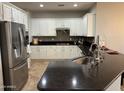 Well-lit kitchen featuring white cabinets, stainless steel appliances, and a dark countertop island at 20980 N Sweet Dreams Dr, Maricopa, AZ 85138